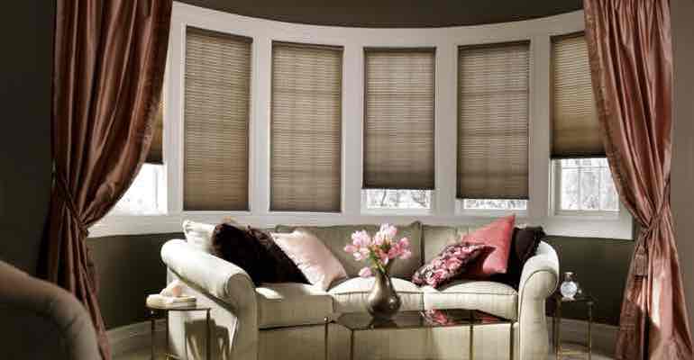 Brown honeycomb shades in lounge bow window.